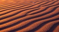 Ripples of fine, golden sand create a mesmerizing pattern under warm, orange Royalty Free Stock Photo
