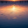 Rippling water reflecting a sunset creates a gradient of warm orange and pink hues Royalty Free Stock Photo