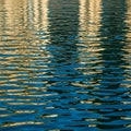 Rippling water surface reflects light and colors, creating a pattern of gold and blue. The Royalty Free Stock Photo