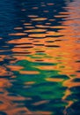 Rippling water surface with vivid reflections in shades of orange, blue, and green. The Royalty Free Stock Photo