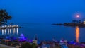 Rise of the moon over the bay of the town Ahtopol with a harbor for fishing boats, pier and lighthouse. Bulgaria. Royalty Free Stock Photo