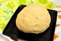 Risen yeast dough for bread or pizza in a black baking tray on a color tablecloth