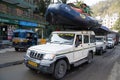 Car carrying a whitewater rafting boat drives through the street, with a man riding on top Royalty Free Stock Photo