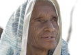 Indian old woman sits on the ghat near the Ganges river in the holy city of Rishikesh, India, close up Royalty Free Stock Photo
