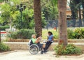 Asian nurse takes a man in a wheelchair for a walk in the park.