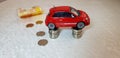 Small red fiat 500 abarth toy stands on four columns of one Israeli shekel coins