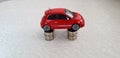 Small red fiat 500 toy stands on four stacks of one Israeli shekel coins