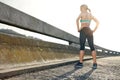 Rising above it all. Rear view shot of an attractive young woman standing on a bridge ready to run.