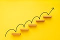 Rising arrow on staircase on yellow background Royalty Free Stock Photo