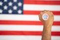 Rising fist with I voted early sticker on hand with US flag as background - Concept of early voting at US election