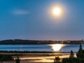 Rising full golden Moon over Umea river delta, summer night with clear skies and tiny white fog over water and coast line. Pine Royalty Free Stock Photo