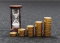 Rising Heaps of Coins on Dark Background with Hourglass Royalty Free Stock Photo