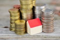 Rising houses prices concept with miniature wooden house and piles of coins on wooden background Royalty Free Stock Photo