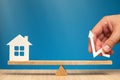 Rising property values. House model and arrow in hand pointing up. Scales as a symbol of the balance of housing prices Royalty Free Stock Photo