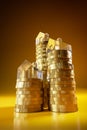 Rising stacks of Euro coins topped with model houses made from acrylic glass. Seamless yellow background and reflections Royalty Free Stock Photo