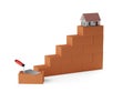 Rising stacks of red brick stones with metal trowel in front and model miniature house on top on white background, construction or