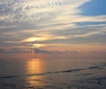 Rising Sun behind Clouds at Horizon with Bright Morning Sky with White Cloud Pattern at Serene Beach Royalty Free Stock Photo