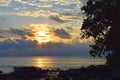 Rising Sun with Golden Sunshine with Clouds in Sky with Lining over Sea and Contours of Tree and Stones - Neil Island, Andaman