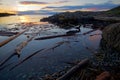 Rising sun lights the distant clouds and nearby driftwood along the coast of southern Saanich Peninsula, Vancouver Island Royalty Free Stock Photo