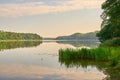 The rising sun and a tranquil lake in a dense forest.