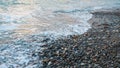 Rising tide cold waves with sea foam and wet pebbles in cloudy bad fickle winter weather. Season changing,global warming theme, Royalty Free Stock Photo