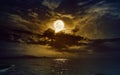 Rising yellow full moon in dark night sky with reflection in water Royalty Free Stock Photo