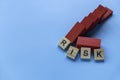 Risk concept with alphabet of risk on unstable structure of red wooden domino on blue background Royalty Free Stock Photo