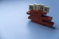 Risk concept with alphabet of risk on unstable structure of red wooden domino on blue background Royalty Free Stock Photo