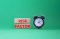 Risk Factor symbol. Wooden blocks with words Risk Factor Beautiful green background with alarm clock. Business and Risk Factor Royalty Free Stock Photo