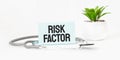 RISK FACTOR word on notebook,stethoscope and green plant