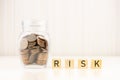 Risk management concept. Coins in jar with wood block cube word RISK. Royalty Free Stock Photo