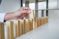 Risk and strategy in business, Close up of business woman hand gambling placing wooden block on a line of domino