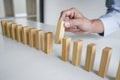 Risk and strategy in business, Close up of business woman hand gambling placing wooden block on a line of domino