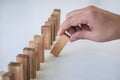 Risk and Strategy in Business, Image of hand gambling placing wooden block on a line of domino, prevention and development to