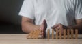 Risk and strategy in business. Man hand stopping wooden block domino business crisis effect or risk protection Royalty Free Stock Photo