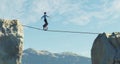 Man ride unicycle on a rope between two mountain cliffs