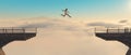 Man jumps over gap of a bridge at high altitude above clouds .