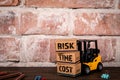 Risk, Time and Cost. Miniature cardboard boxes and a forklift on a wooden office table Royalty Free Stock Photo