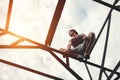 Risky brave man balancing and sitting on high metal construction