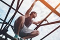 Risky brave man climbing and sitting on high metal bridge Royalty Free Stock Photo