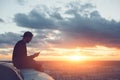 Risky man with smartphone chilling on the edge of the roof at sunset Royalty Free Stock Photo