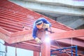 Risky welder while climbing and welding on top of the steel roof structure work at the building construction site. Skilled worker