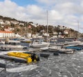 Risor, Norway - March 16, 2018: Ice floating in the sea at the harbour of Risor, Norway. Small boats at the pier