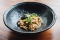 Risotto with mushroom, fresh herb and parmesan cheese in black plate on wooden table Royalty Free Stock Photo