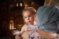 The ritual of baptism. A Christian church painted on the walls icons. two-year-old girl in the arms of a godmother Royalty Free Stock Photo