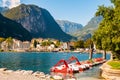 Beautiful Riva del Garda cityscape with vibrant red pedal boats parked in a row on the beach and city surrounded by high dolomite Royalty Free Stock Photo