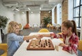 Rivalry. Two little children, boy and girl shaking hands after match, playing board game, sitting together at the table Royalty Free Stock Photo