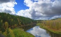 river against autumn forest with yellow and green trees and bright colorful blue sky with clouds. Royalty Free Stock Photo