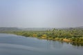 River bank with bright fresh green forest and palm trees under a clear blue sky, aerial view Royalty Free Stock Photo