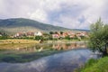 River bank. Mountains, clouds and small town are reflected in water. Bosnia and Herzegovina, view of Trebisnjica river Royalty Free Stock Photo